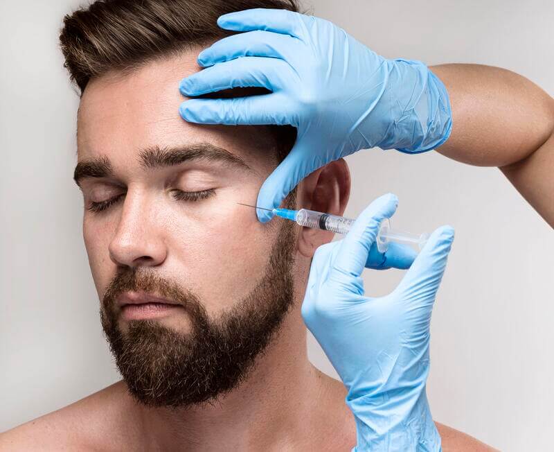 Un hombre recibe una inyección en su rostro durante un tratamiento de retoque facial. La inyección puede ser utilizada para rejuvenecer la piel y reducir las arrugas y líneas de expresión.